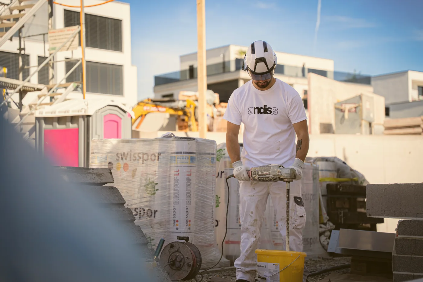 Andisa-Mitarbeiter mit Rührwerk zwischen Dämmmaterial auf der Baustelle