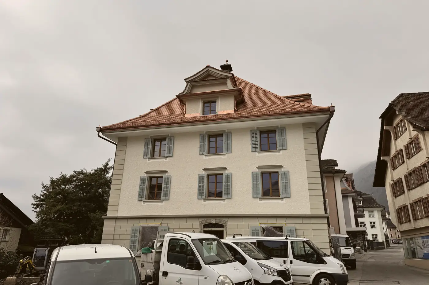 Renoviertes Altbauhaus mit Walmdach und Fensterläden, davor Lieferwagen