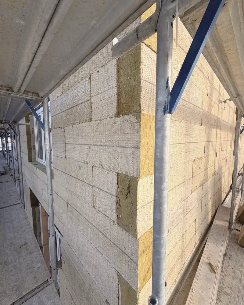 Fassade mit frisch angebrachten Dämmplatten, davor das Gerüst