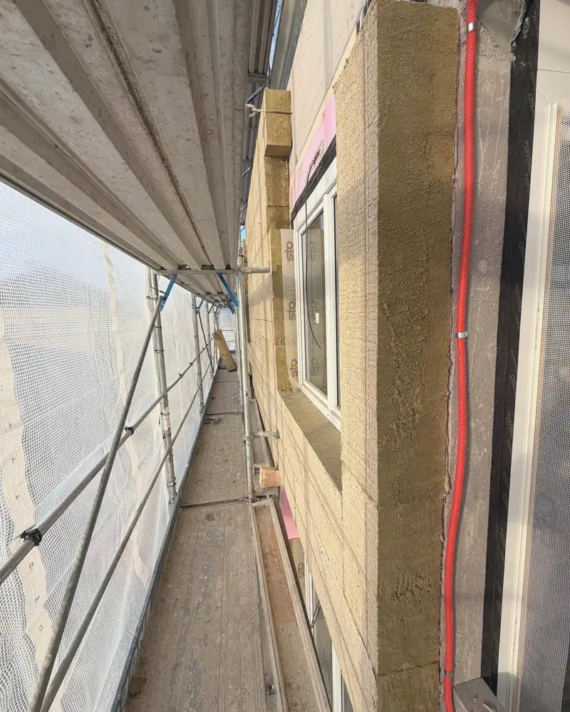 Gerüstgang entlang einer gedämmten Fassade mit Fenstern