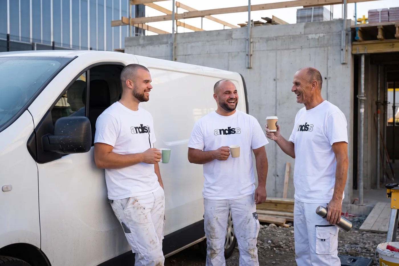 Drei Vorarbeiter in Andisa-Shirts bei einer kurzen Pause am Bus