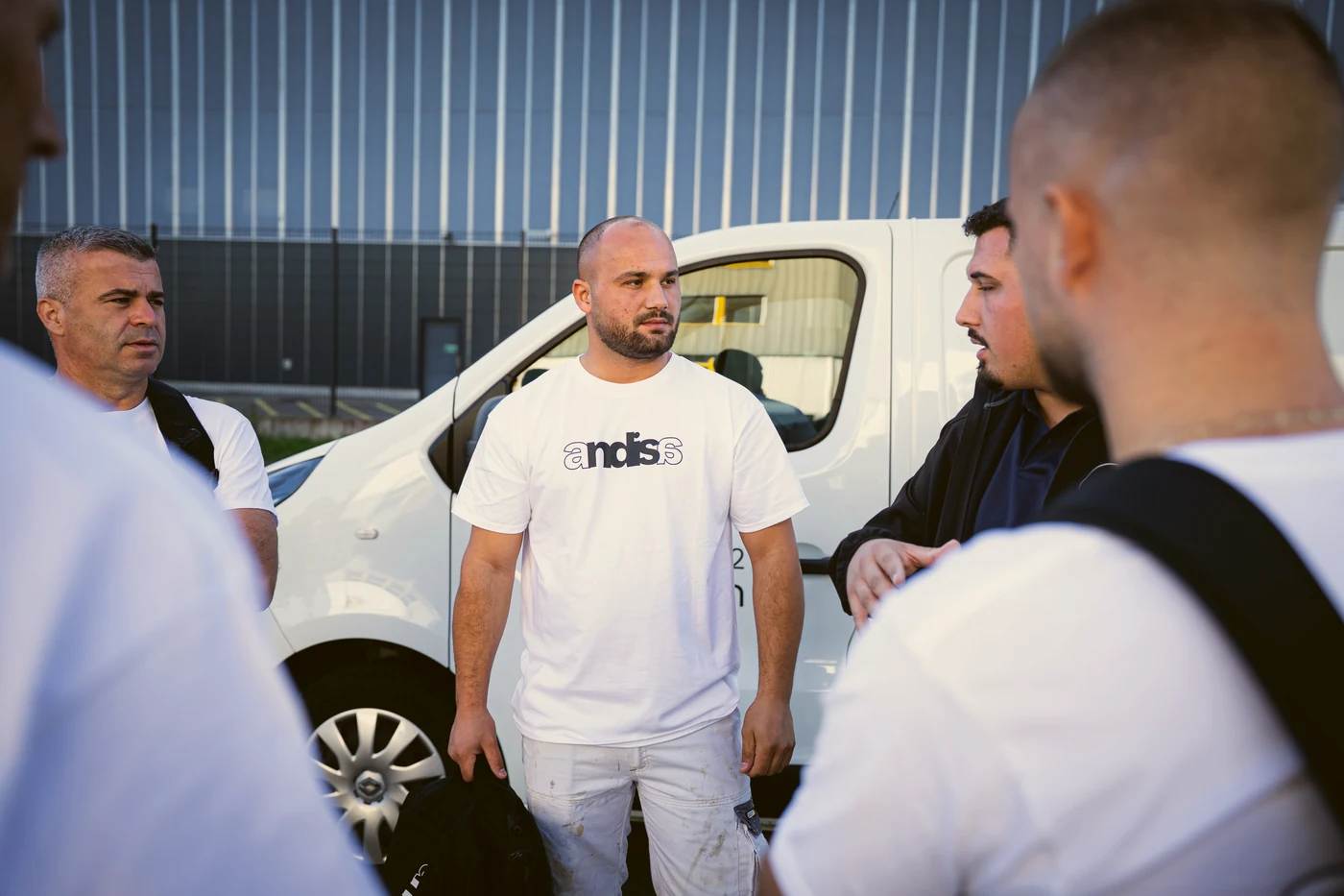 Vorarbeiter im Andisa-Shirt mit Kollegen am Firmenbus